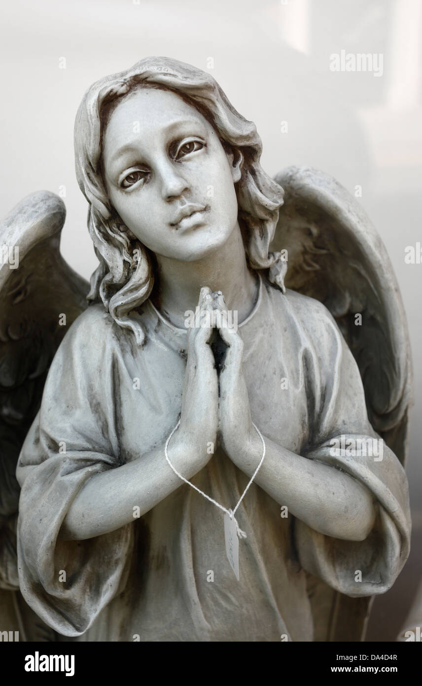 A religious statue on display in a shop window depicting an angel with a price tag. Stock Photo