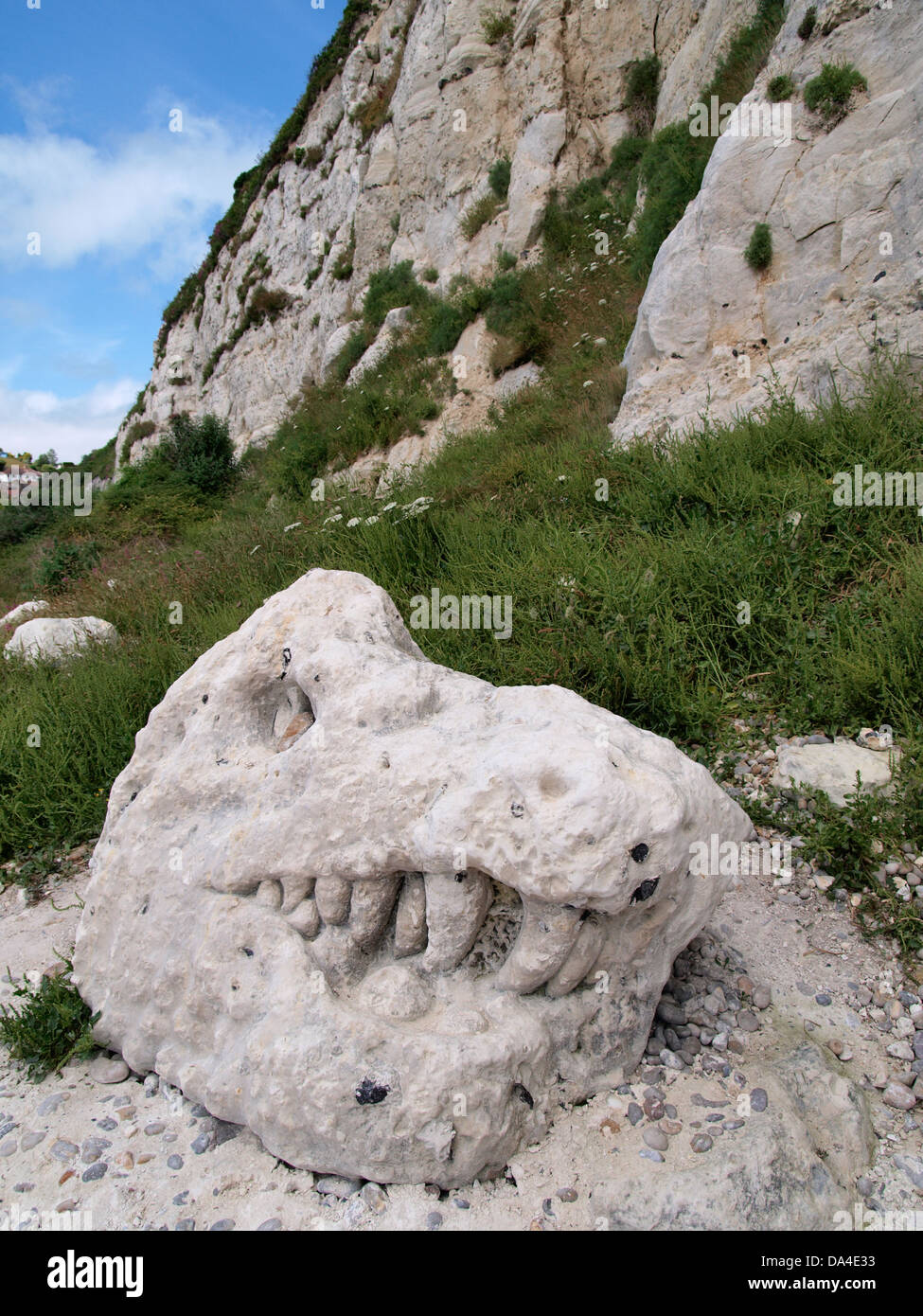 Dinosaur head carved into stone at the bottom of cliffs, Beer, Devon, UK Stock Photo