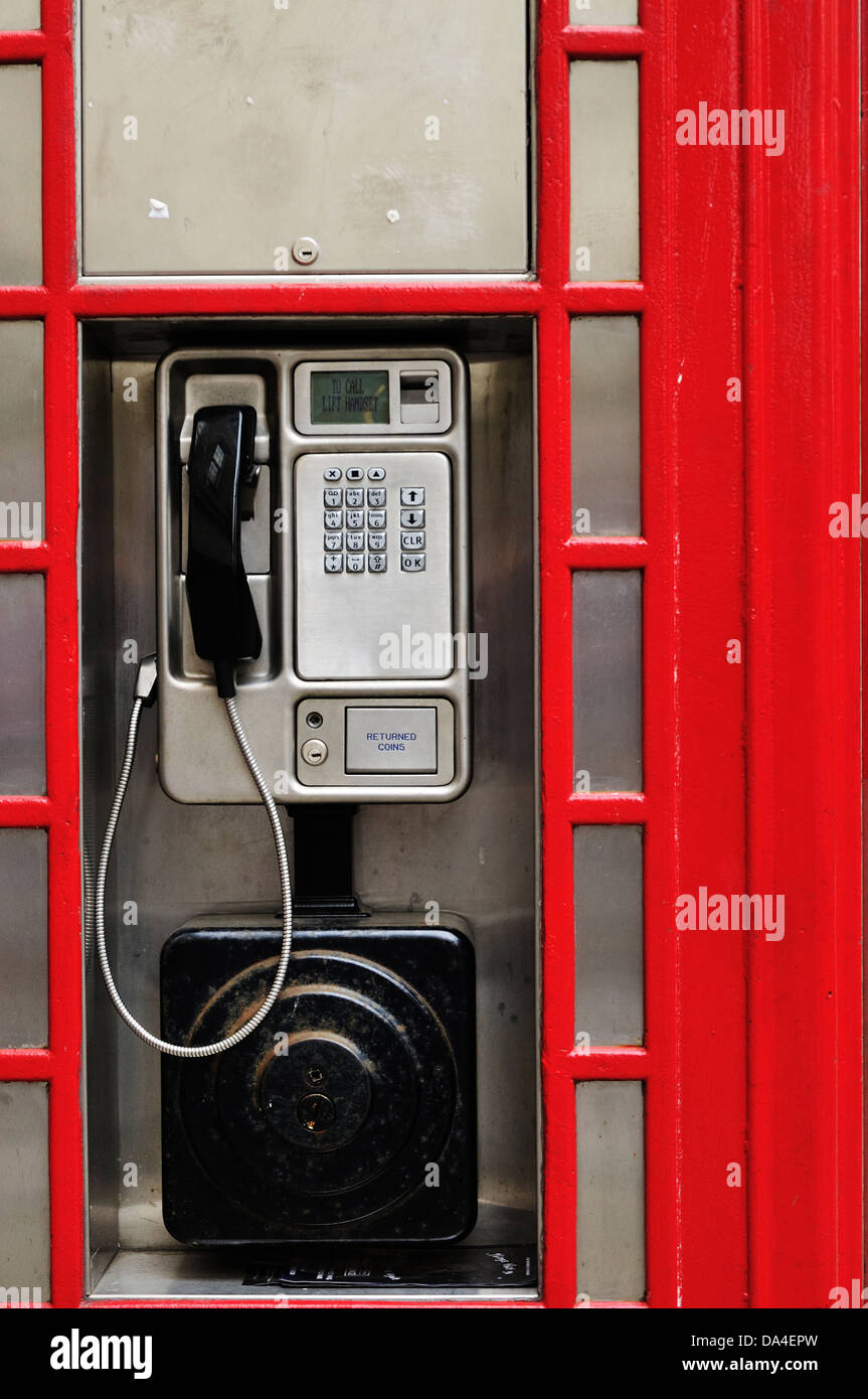 A modern public telephone fixed to the outside of a traditional looking replica red telephone booth Stock Photo