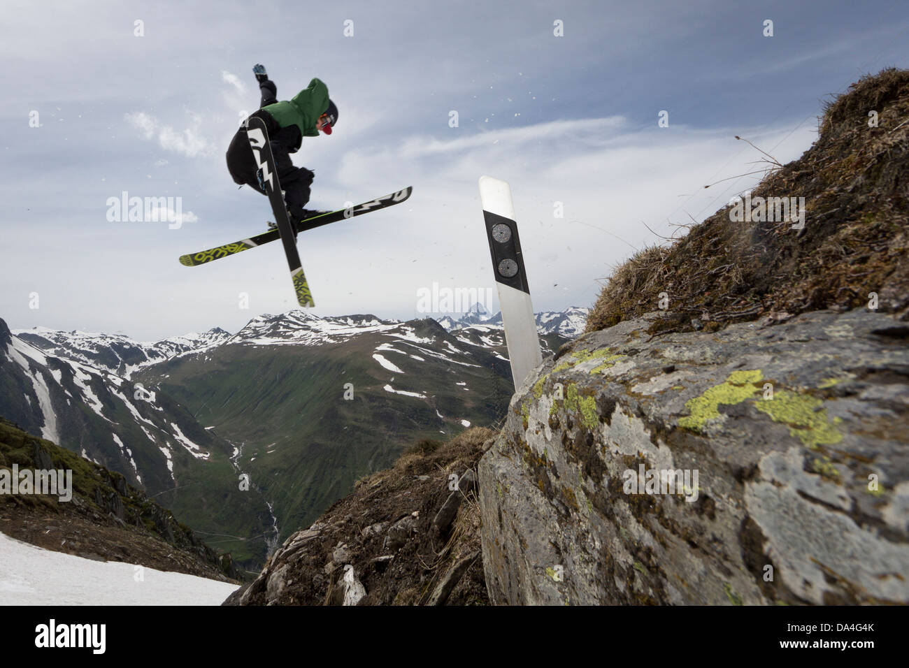 NUFENEN, VALAIS, SWITZERLAND. A freestyle freeskier is executing a trick on a handmade kicker to jump over a road marker. Stock Photo