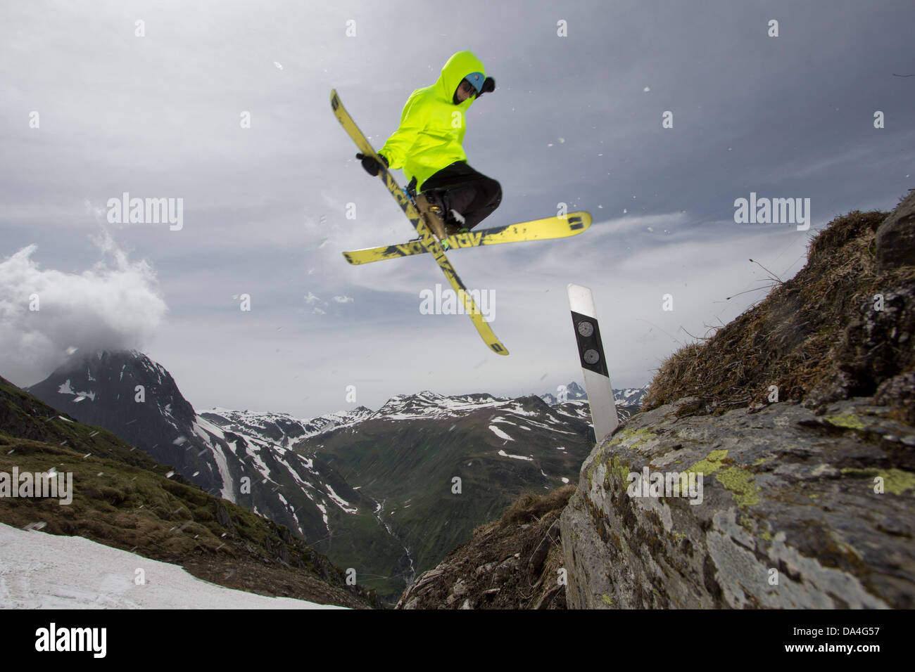 NUFENEN, VALAIS, SWITZERLAND. A freestyle freeskier is executing a trick on a handmade kicker to jump over a road marker. Stock Photo