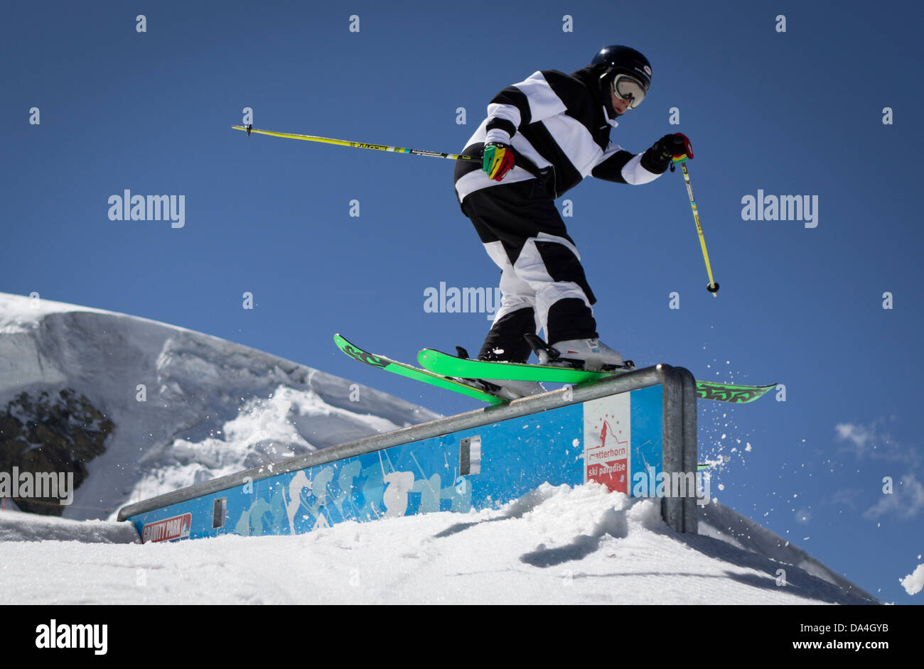 A freeskier in a black/white dress sliding down a rail in the Gravity Snowpark in Zermatt, Switzerland. Stock Photo