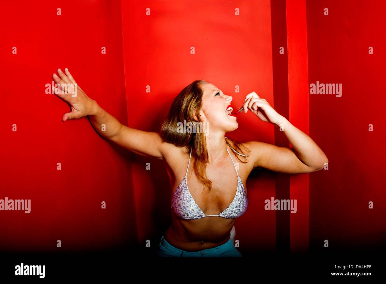 A young pretty woman applying red lipstick Stock Photo
