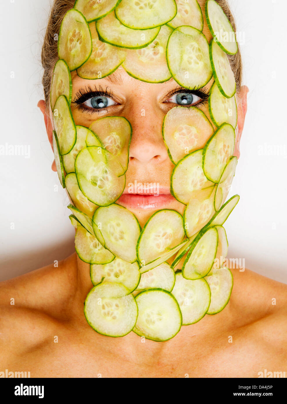 woman with slices of cucumber covering her face Stock Photo