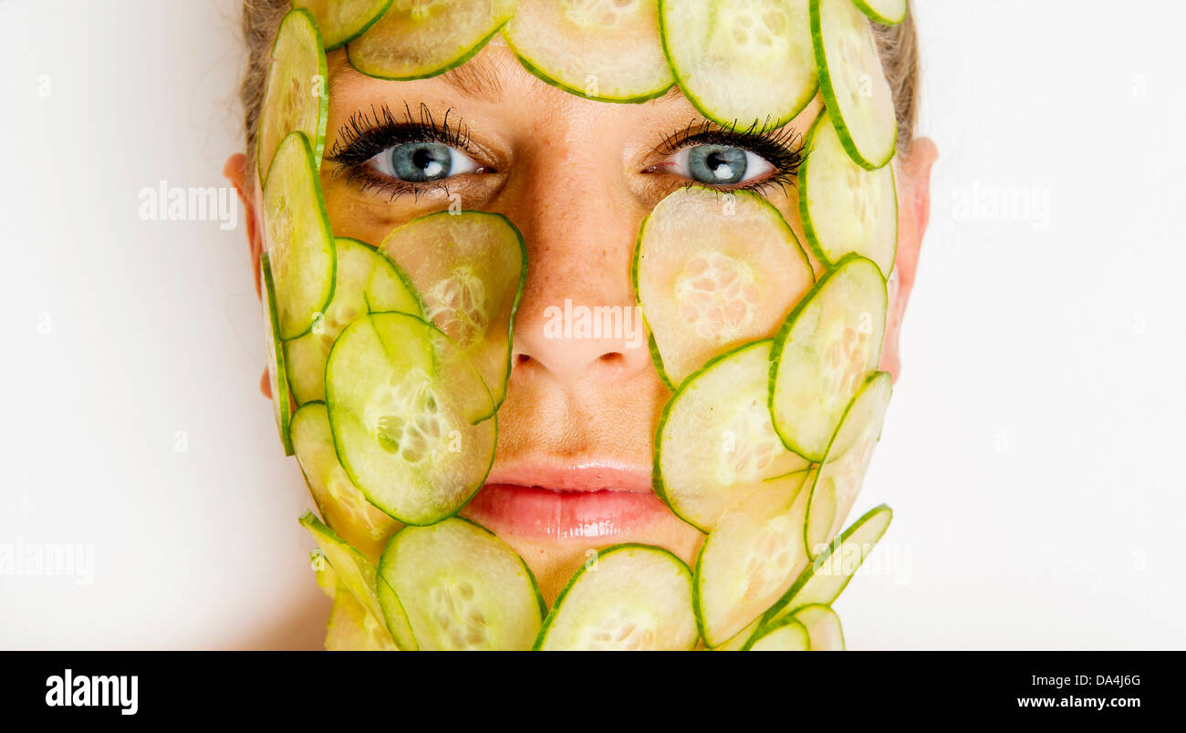 woman with slices of cucumber covering her face Stock Photo