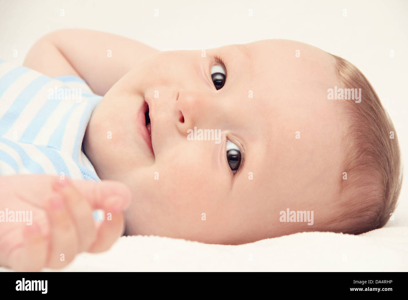 happy baby lies on back on white bed Stock Photo