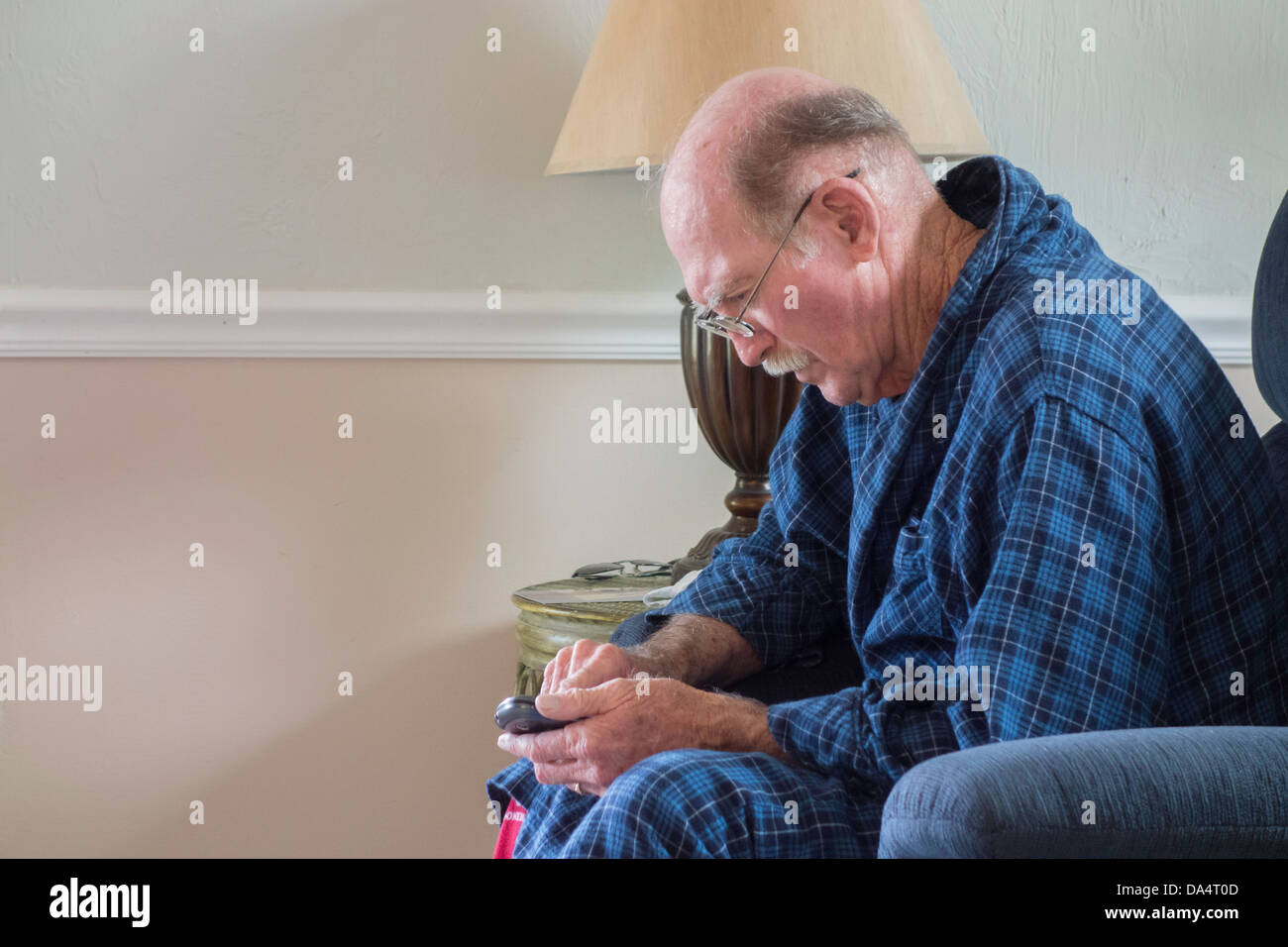 A 75 year old man with Alzheimer's struggles with the settings of his cell phone. USA. Stock Photo