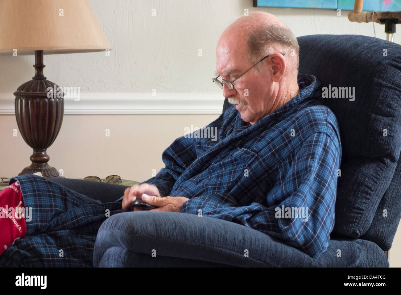 A 75 year old Caucasian man with Alzheimer's struggles with the settings of his cell phone. USA Stock Photo