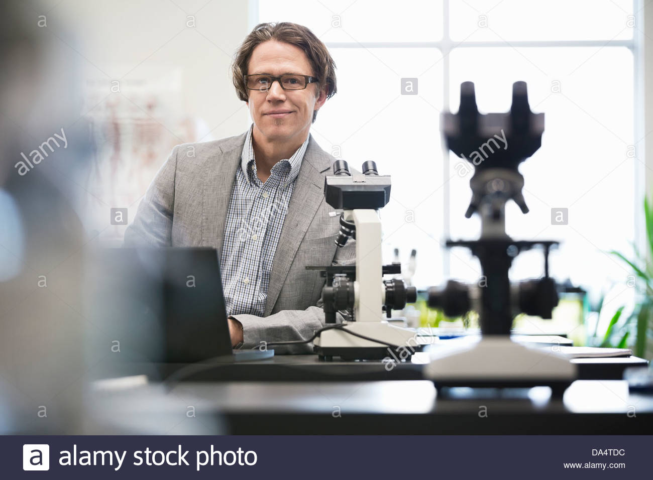 Portrait of male college professor leaning on table in science lab Stock Photo