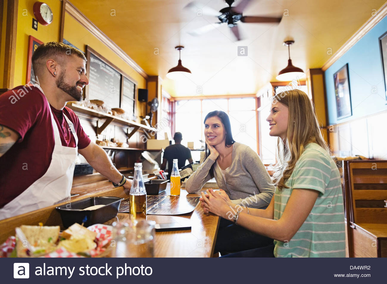 Male deli owner talking to customers at deli counter Stock Photo Alamy