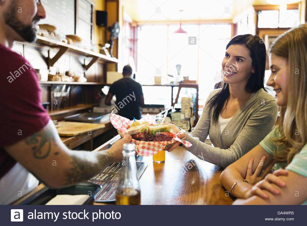 Male deli owner serving food to customers at counter Stock Photo Alamy