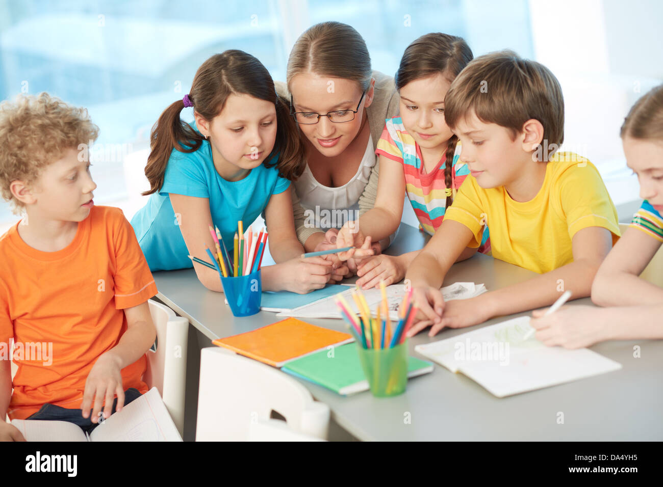 Portrait of diligent schoolkids and their teacher interacting at lesson ...