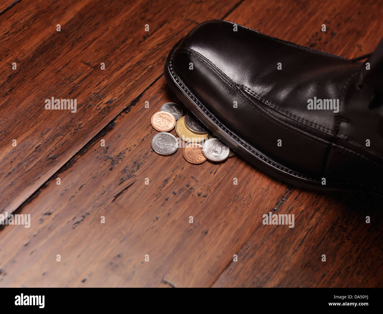 Finding money concept of a man shoe stepping on change coins on the floor. Stock Photo