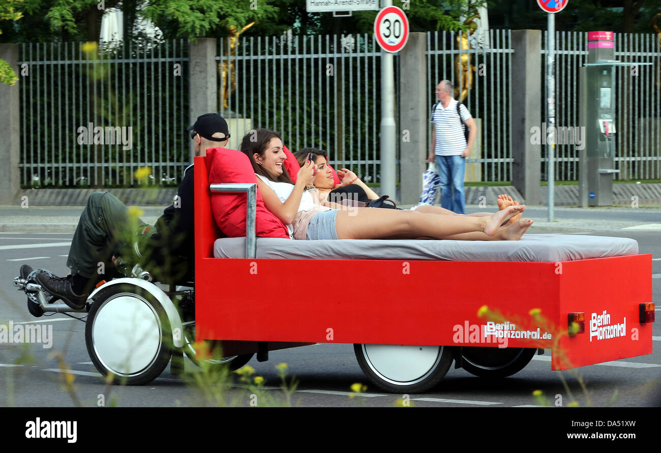 Two young women are driven on a 'Bettbike' ('bed bike') through Berlin,  Germany, 03 July 2013. Entrepreneur Richard Eckes and his company Berlin  Horizontal offer rides to guests on this newly invented