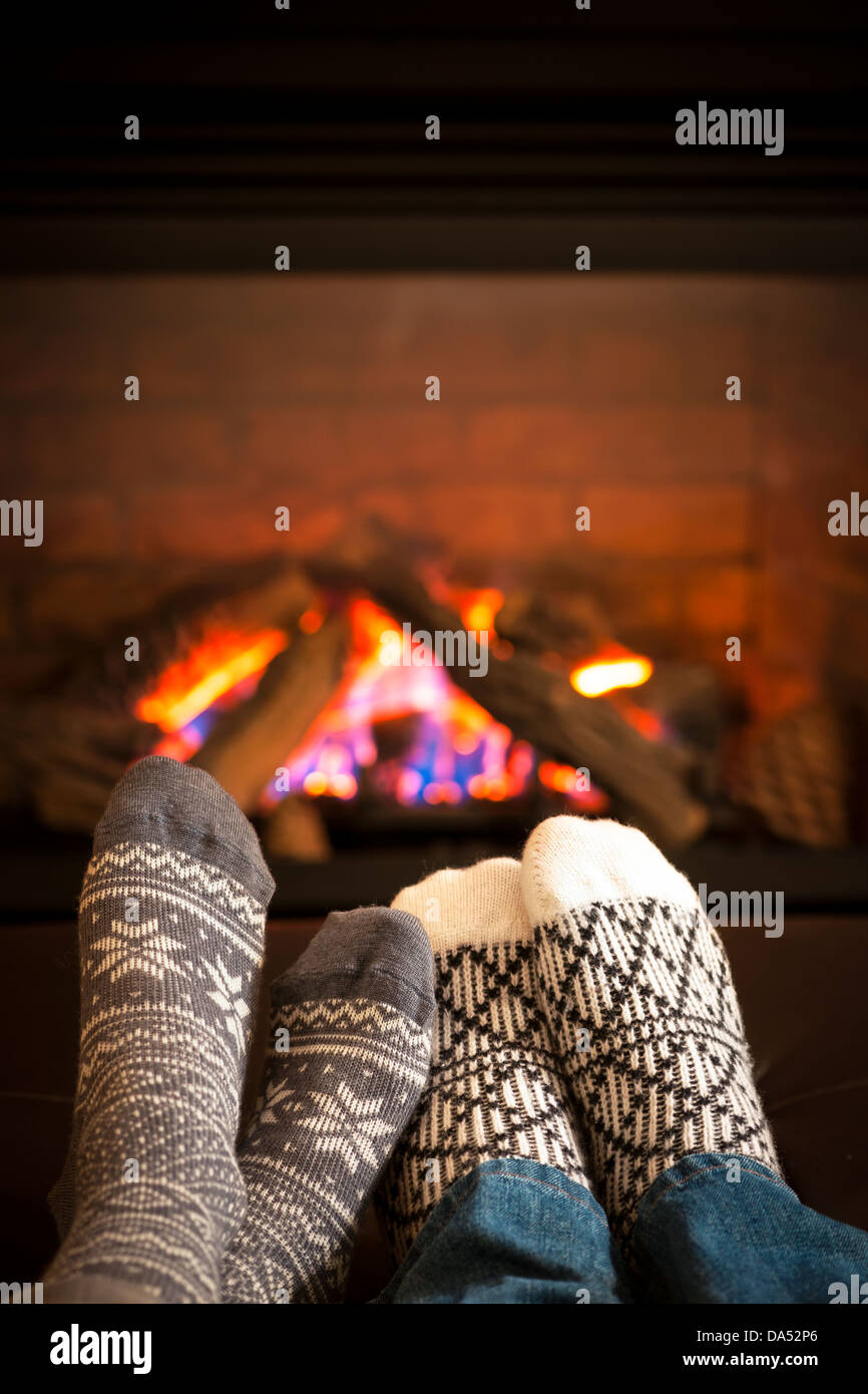 Feet in wool socks warming by cozy fire Stock Photo