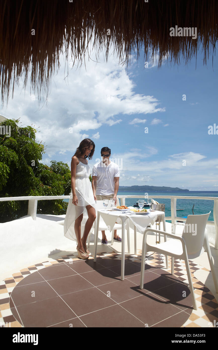 A young couple sitting at a table by the sea. Stock Photo