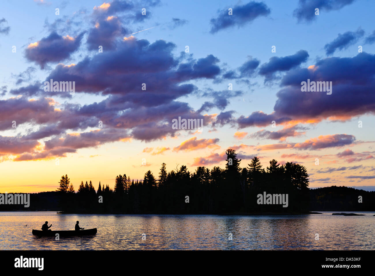 Silhouette of island and canoe on lake at sunset in Algonquin Park, Canada Stock Photo
