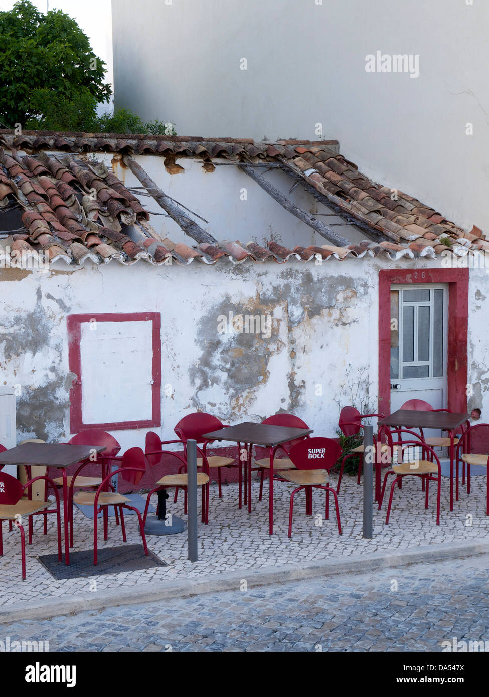 strange scene in Cabanas de Tavira, Algarve, Portugal where the space in front of a derelict building is being used by a cafe Stock Photo