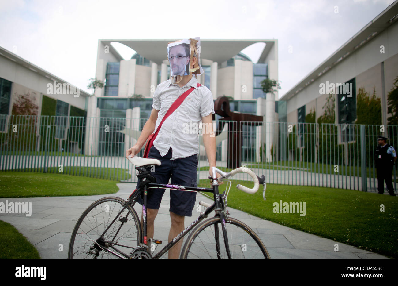 Berlin, Germany. 04th July, 2013. A democracy activist stands with a mask of the portrait of Edward Snowden in front of the German Chancellery in Berlin, Germany, 04 July 2013. Snowden made the supposed data espionage of the USA and Great Britain public. Photo: KAY NIETFELD/dpa/Alamy Live News Stock Photo