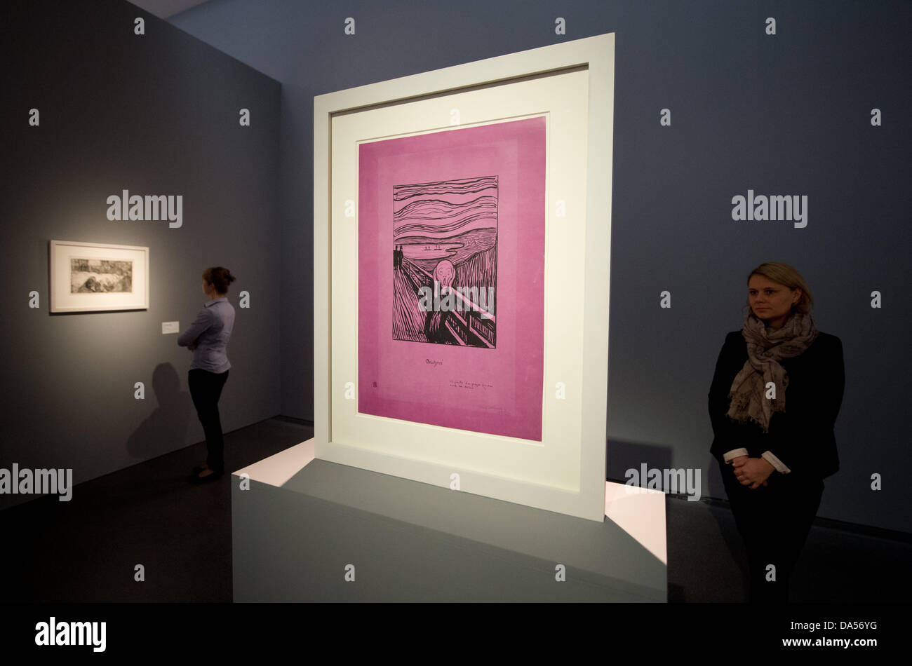 A women looks at a lithograph by Edvard Munch from 1985 during a media event at the Staatsgalerie in Stuttgart, Germany, 04 Juy 2013. The Staatsgalerie has the only print on purple paper of the famous motive 'Der Schrei' ('The scream') which was actually called 'Geschrei' ('Screams') by the artist. From 05 July until 06 October 2013 the Staatsgalerie shows about 65 artworks of the Norwegian painter and graphic artist in the exhibition called 'Vom ersten Kuss bis in den Tod' ('From the first kiss until death'). Photo: MARIJAN MURAT Stock Photo