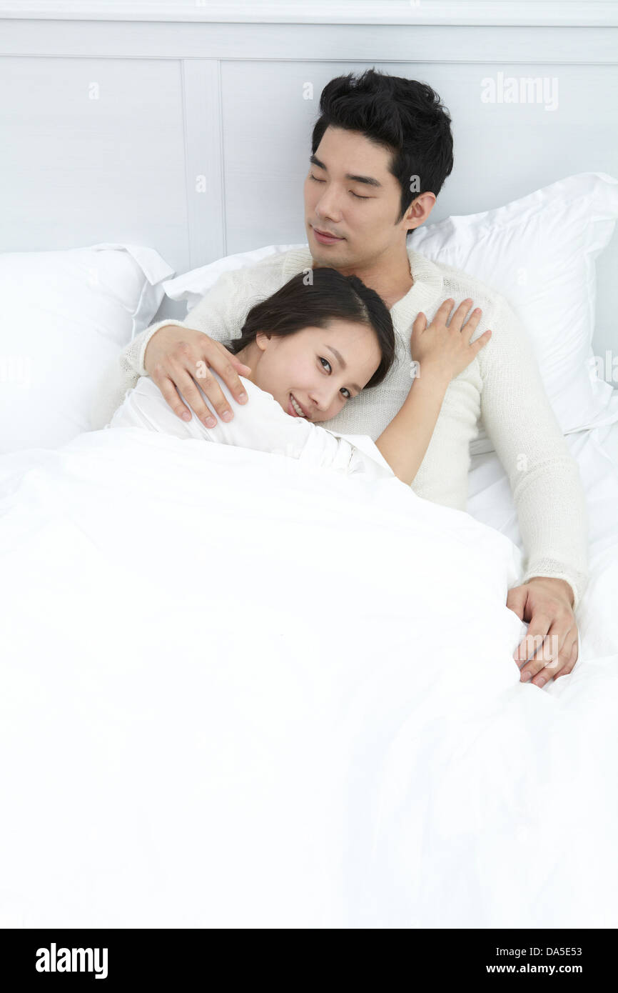 A young couple posing on a bed together. Stock Photo