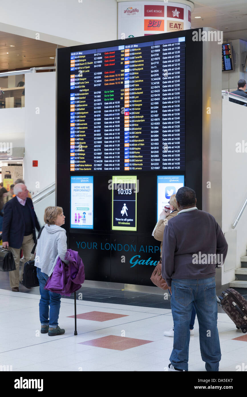 Passengers checking departure board at Gatwick Airport. Stock Photo