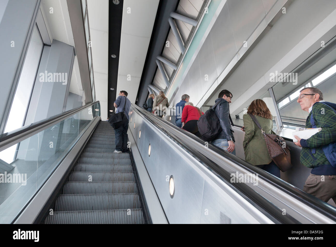 passengers on up escalator at airport Stock Photo