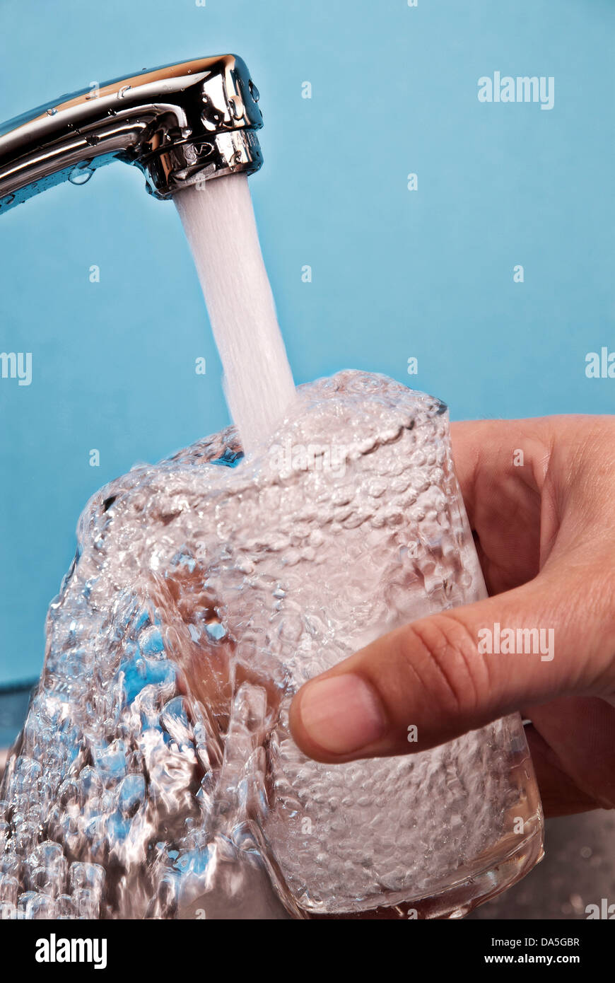 Water flowing from a faucet into a glass. Stock Photo