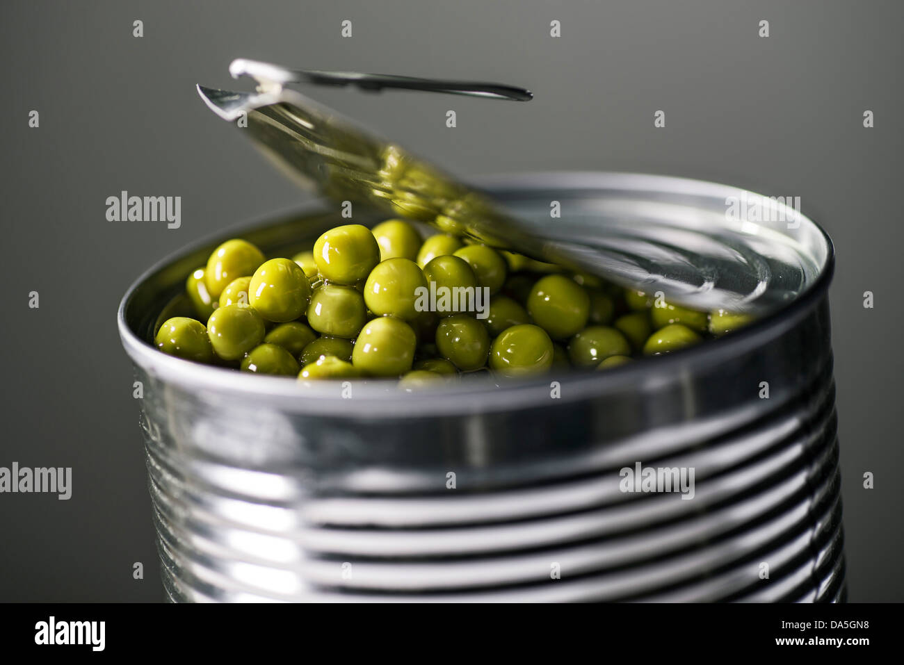 A tin can with the lid open. Peas can be seen. Stock Photo