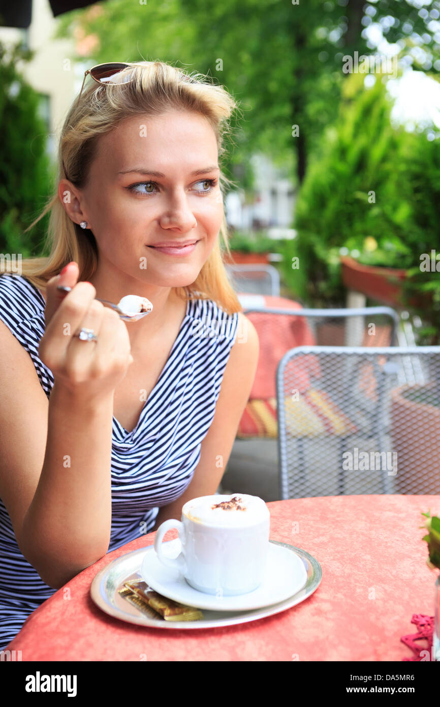 a young woman sitting at a sidewalk cafe Stock Photo - Alamy