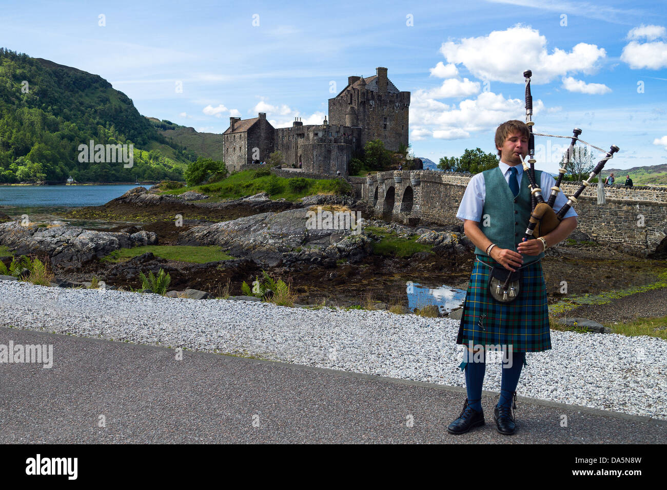 Europe Great Britain, Scotland, Highlands, a bagpipe player and the Eilean Conan castle in background. Stock Photo
