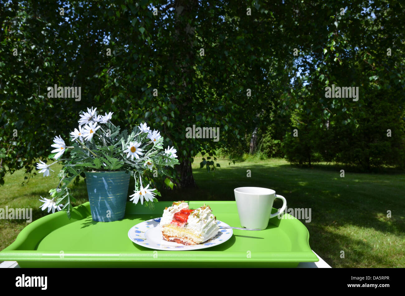 Made table with flowers, strawberry cake and a cup for coffee Stock Photo