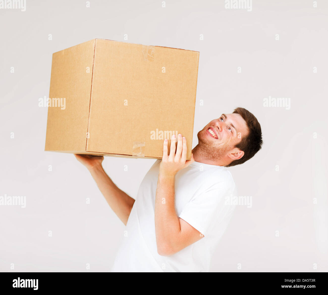 Человек держит тяжелый груз. Человек несет коробку. Коробка в руках. Человек поднимает коробку. Несет тяжелую коробку.