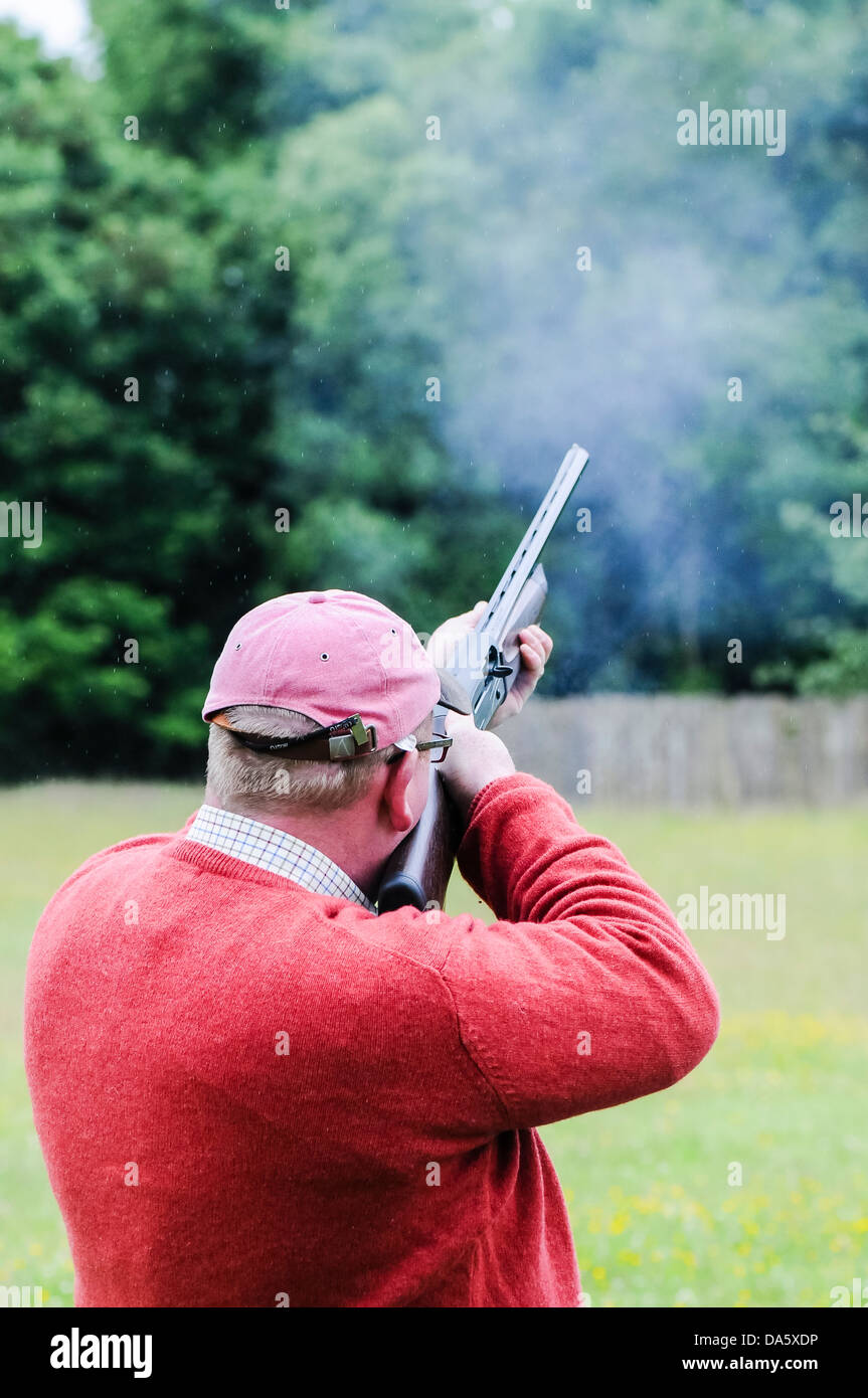A man fires a shotgun while shooting clay pigeons Stock Photo