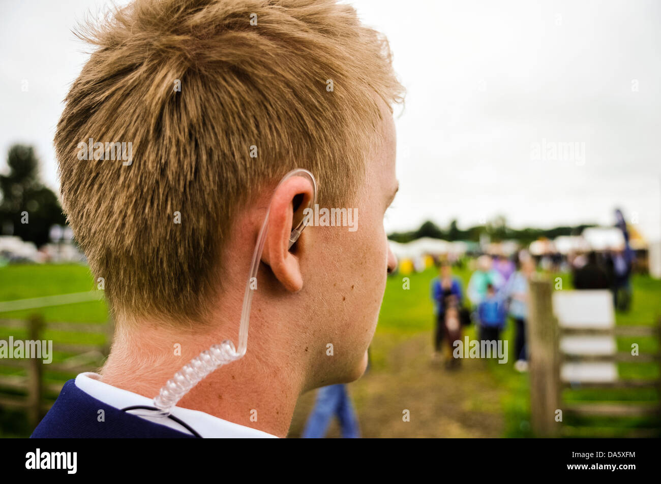 A young security guard wearing a coiled earpiece to listen to his two-way radio Stock Photo