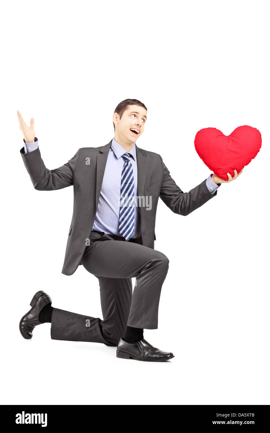 Handsome male in a suit kneeling with red heart isolated on white ...