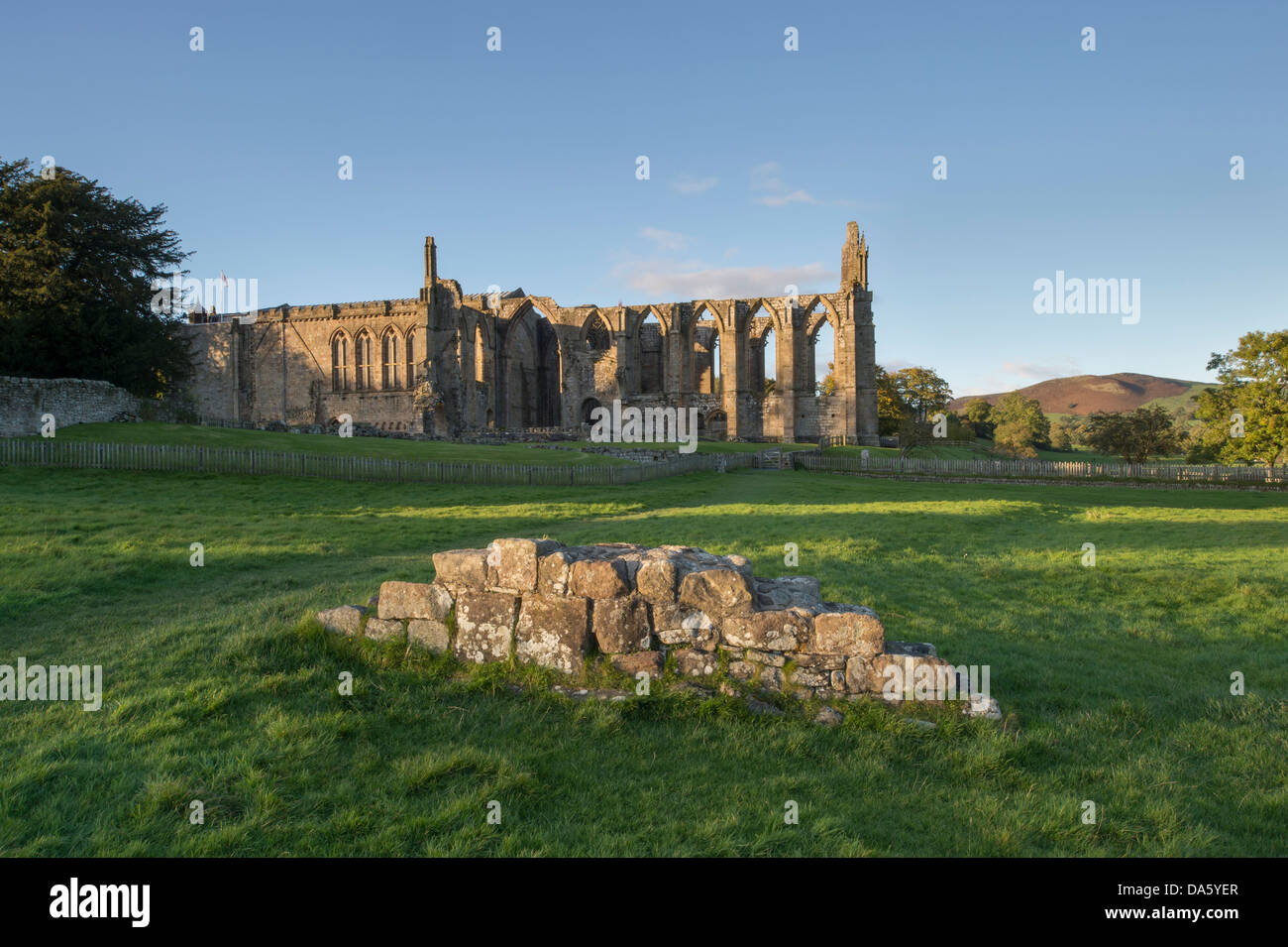 View from south of sunlit, ancient, picturesque monastic ruins of Bolton Abbey & priory church, in scenic countryside - Yorkshire Dales, England, UK. Stock Photo