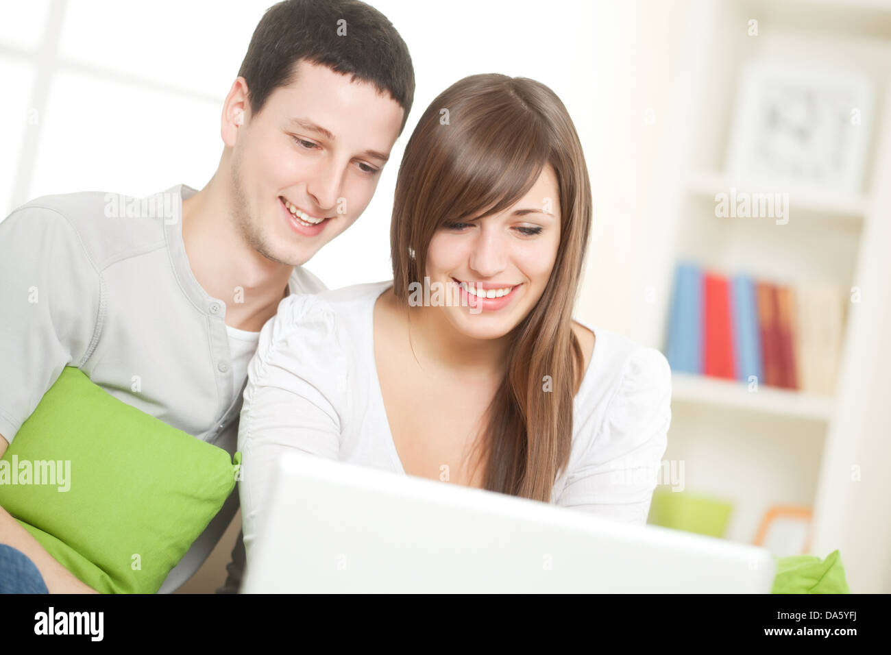 Portrait of a happy couple using their laptop in the living room. Stock Photo