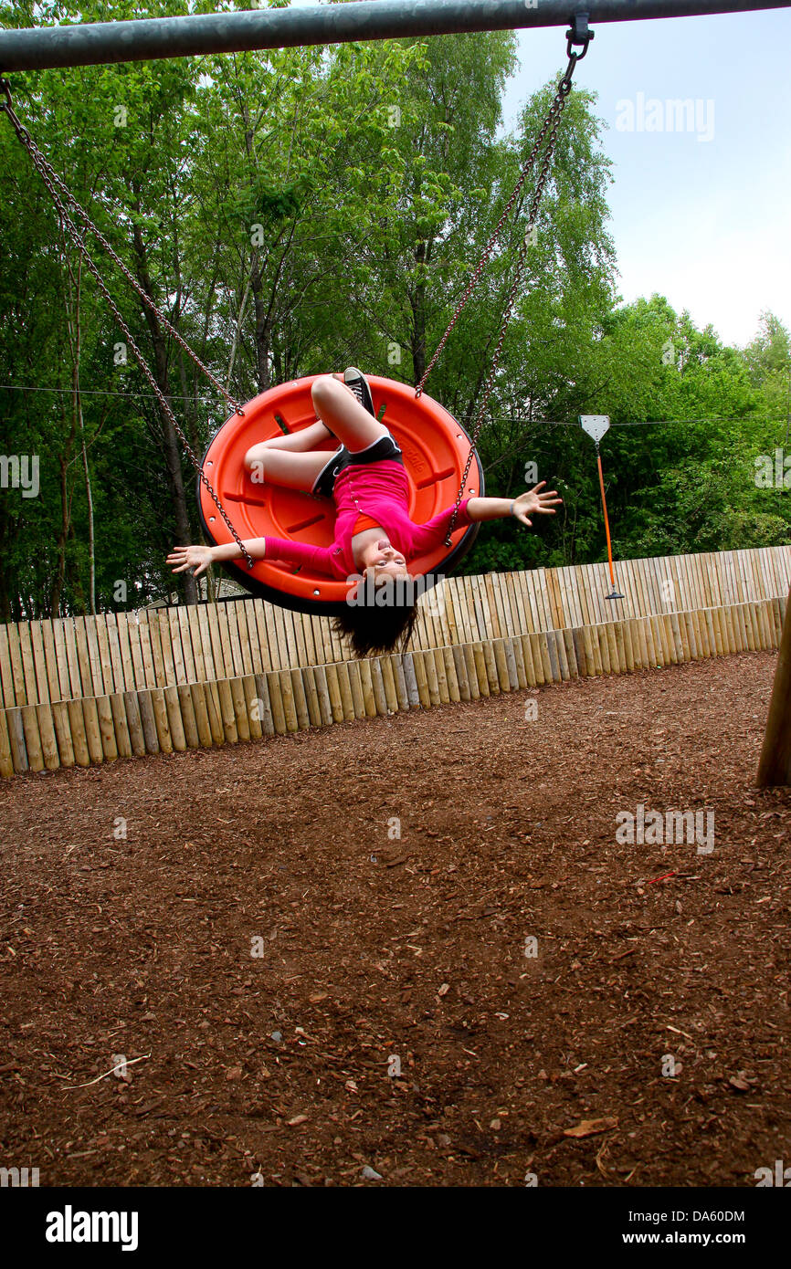 Young girl upside down on plastic disc swing Stock Photo