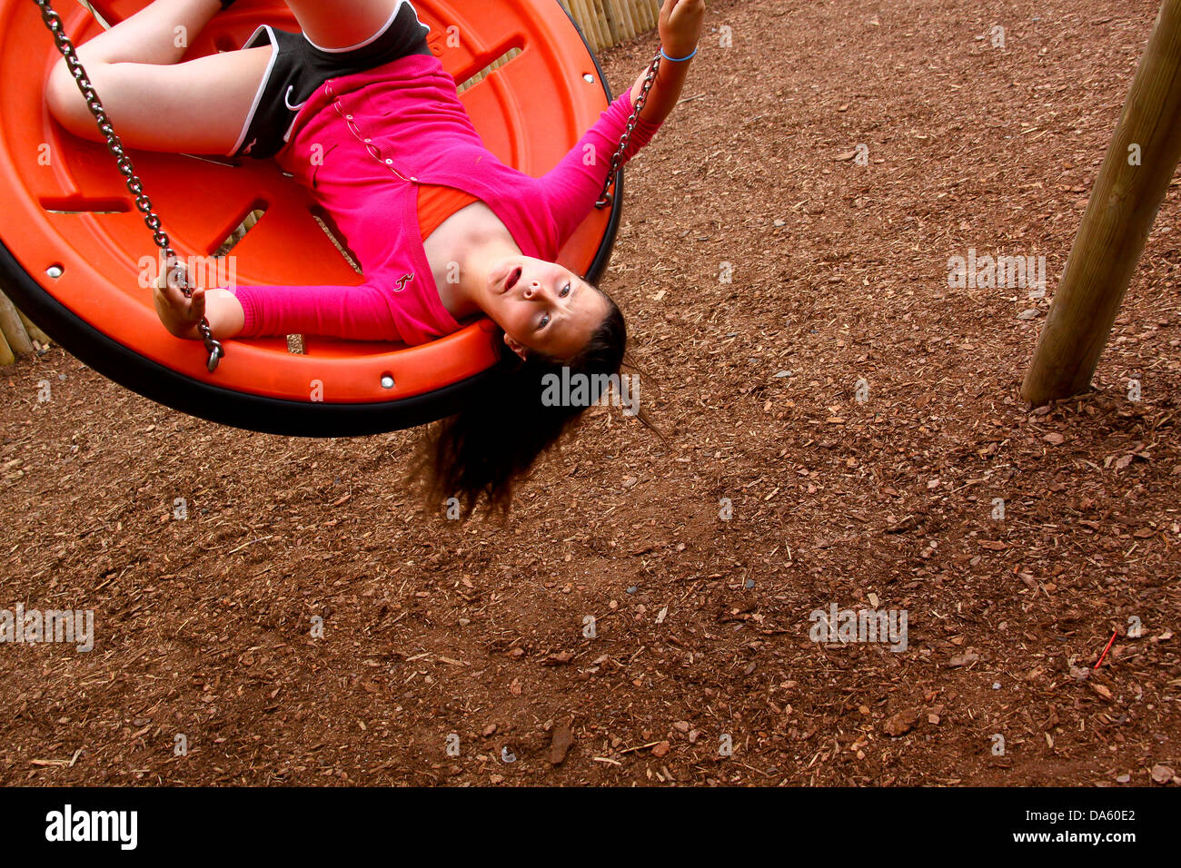 Young girl upside down on plastic disc swing Stock Photo