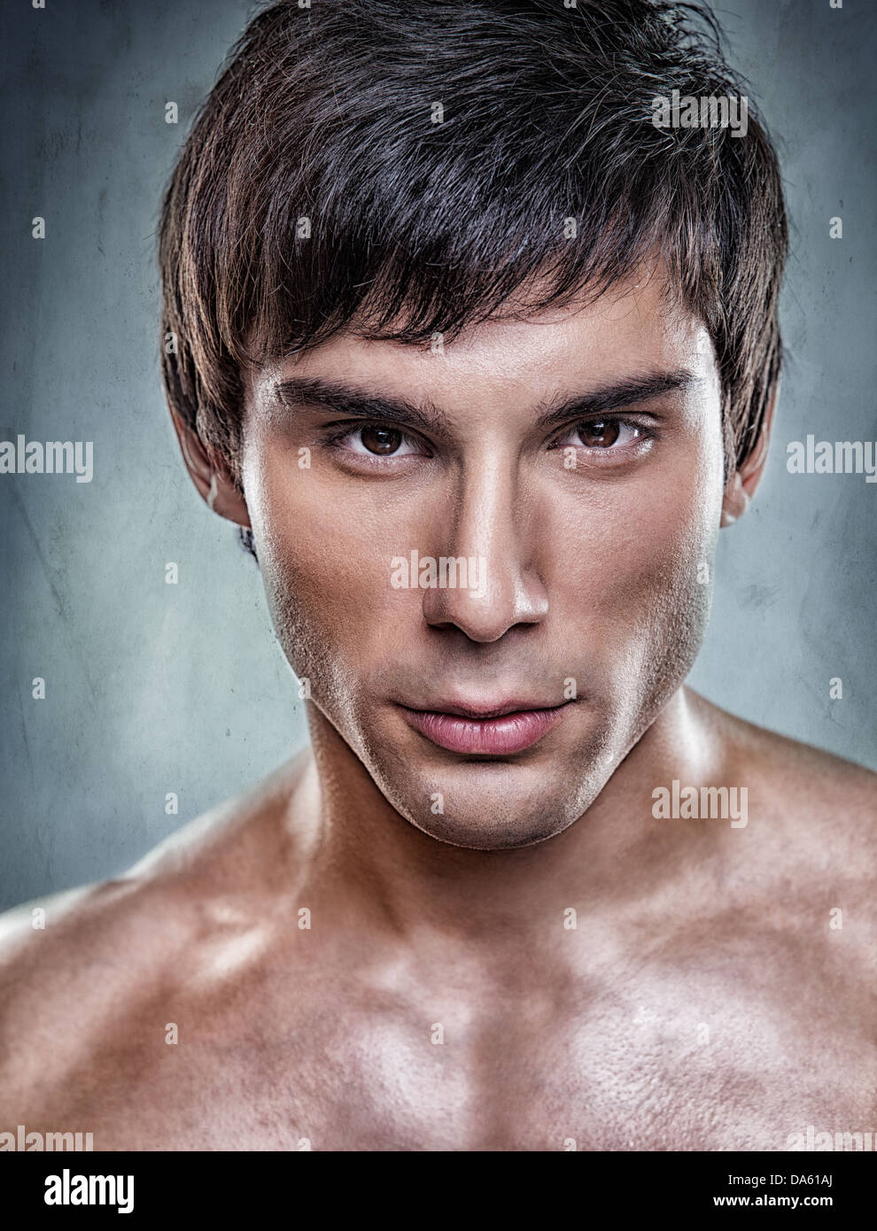 A handsome model posing in front of a gray background. Stock Photo