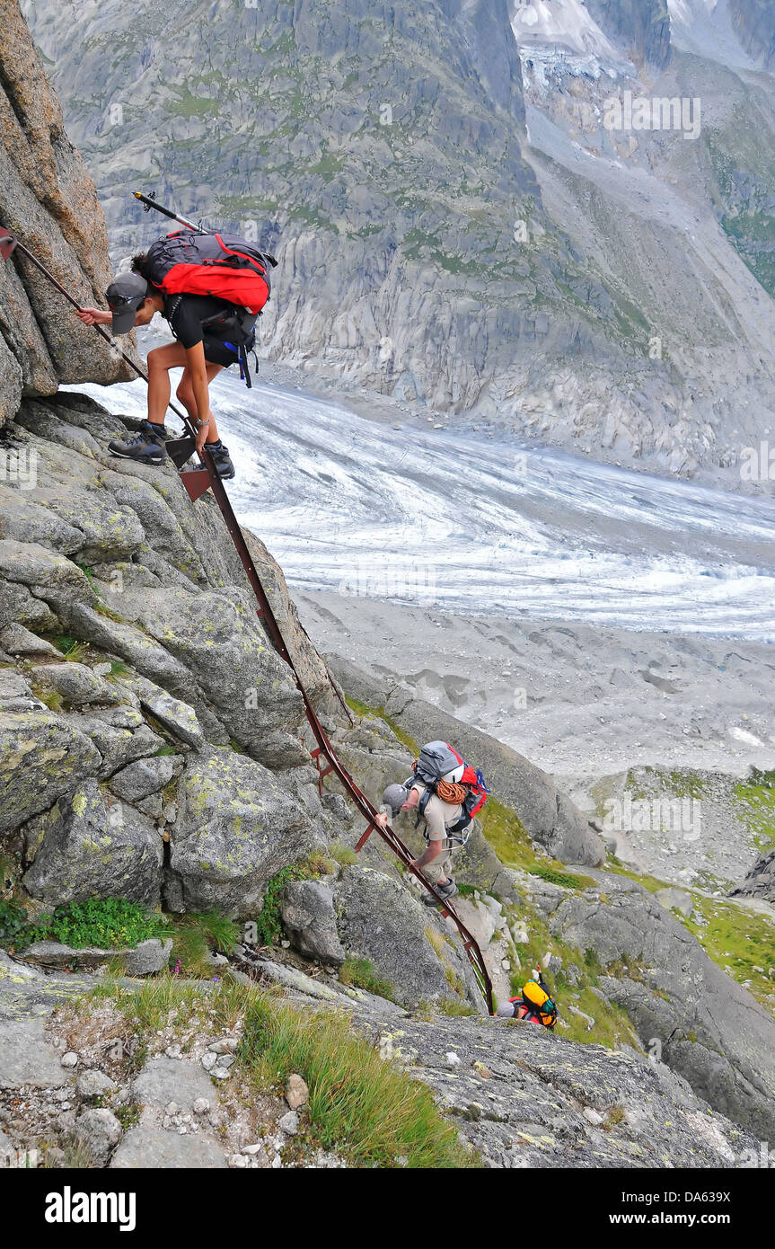 girl climber on a rock face ladder, climbing down with glacier in the background and no security Stock Photo