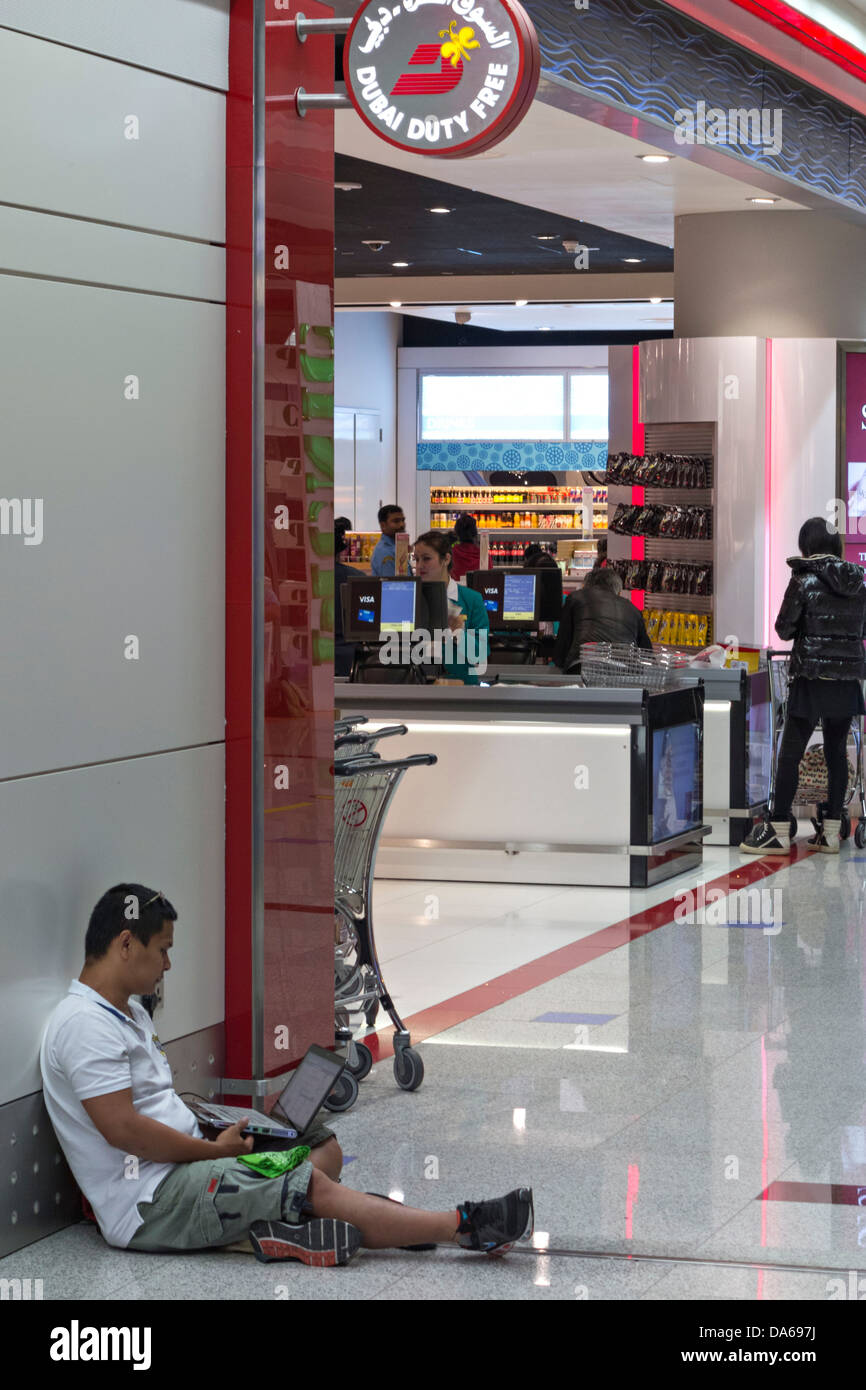Man sitting on floor with laptop, Transfer Terminal, Dubai International Airport Terminal, Dubai, United Arab Emirates Stock Photo