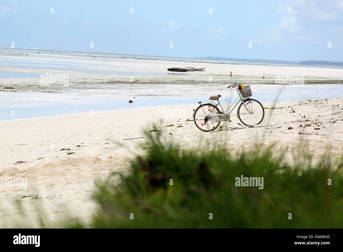 An abandoned bicycle parked on a white sandy beach paradise in Zanzibar with blue waters Stock Photo