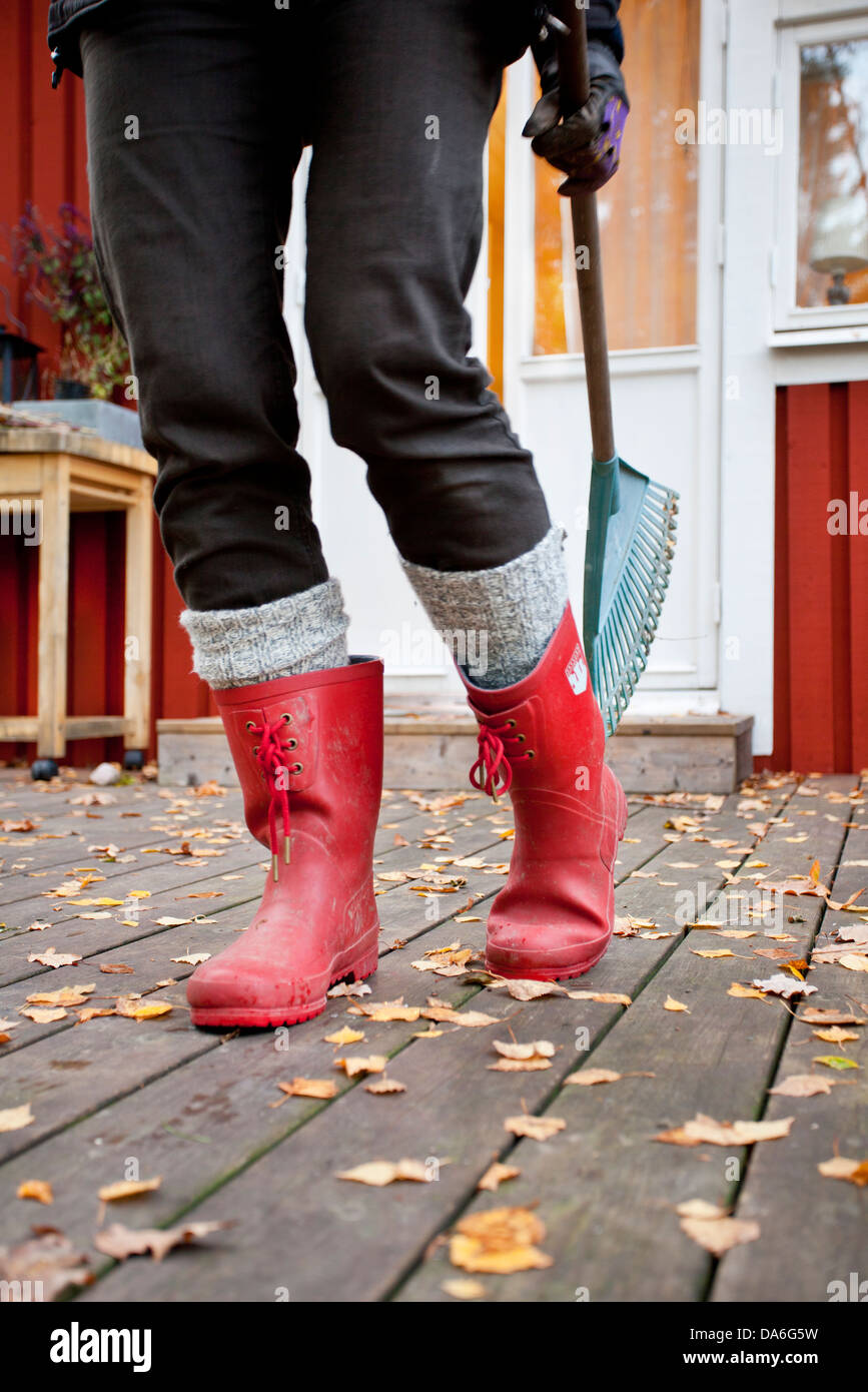 Woman wearing rubber boots holding rake Stock Photo Alamy