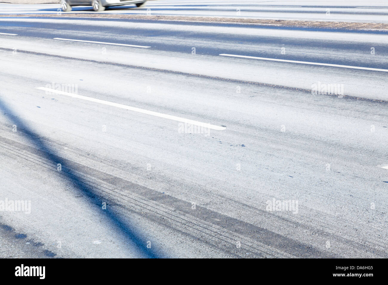 Abstract view of a road surface after winter salting showing shadows, markings and tyre marks Stock Photo