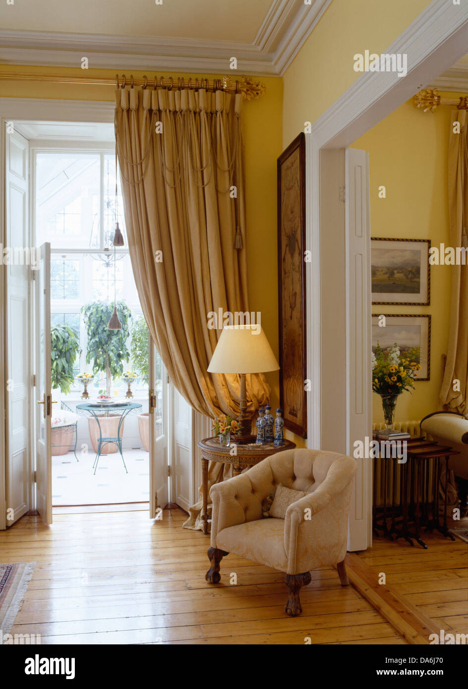 Cream tub chair beside double doorway in drawing room with lighted