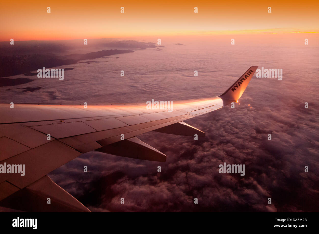Wing of an airplane on cloud sky at dusk Stock Photo