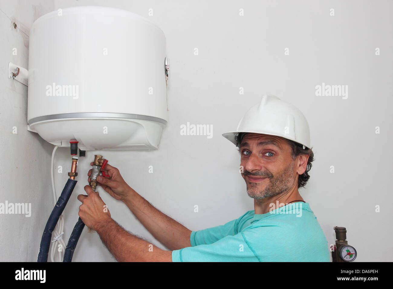 Happy plumber installing an electric water heater Stock Photo Alamy
