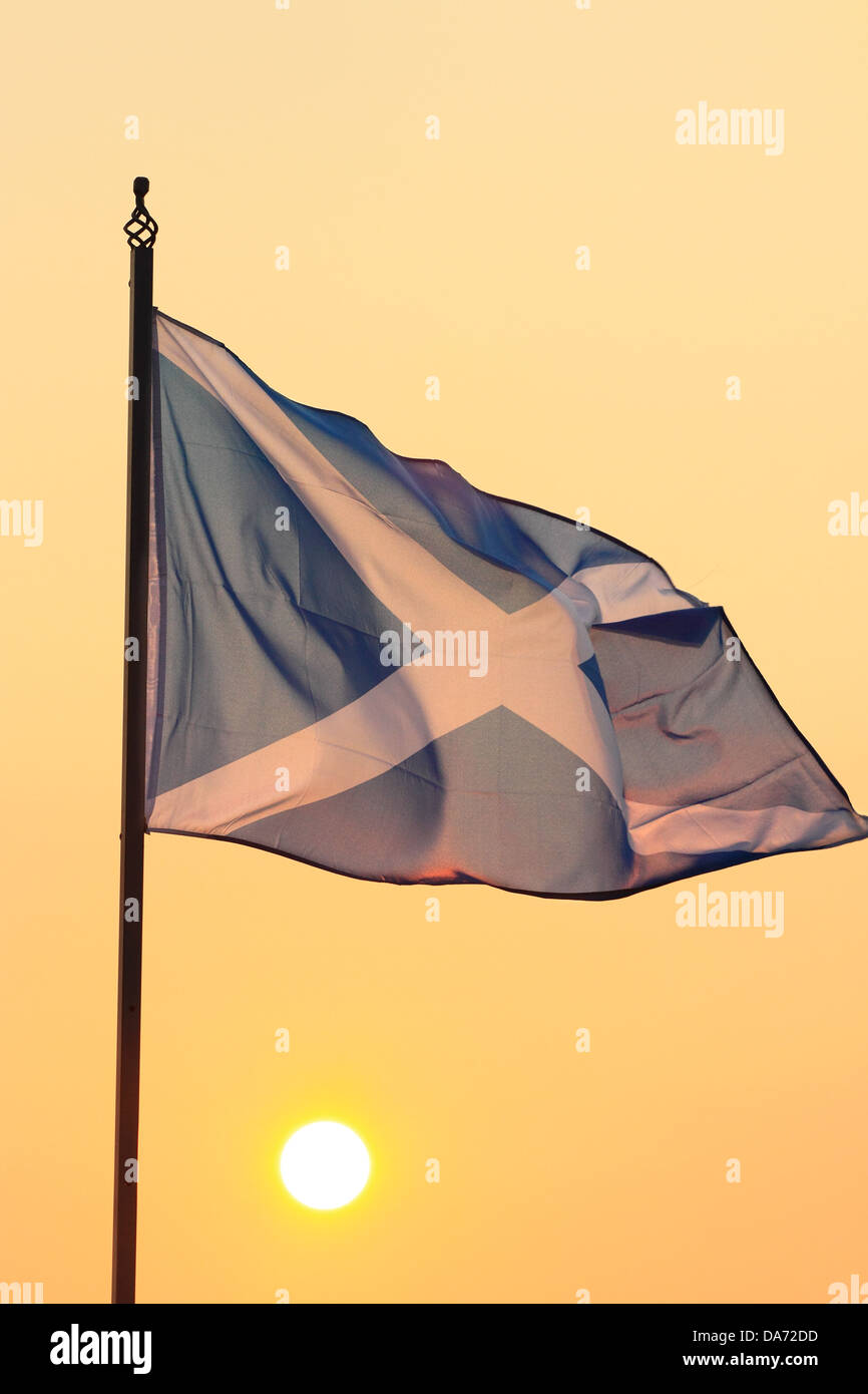 The sun rises behind the Saltire flag, Scotland's national heraldic symbol. Stock Photo